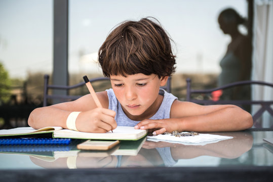 Boy at table writing in workbook