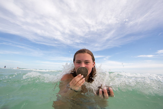 Portrait of young woman in water, holding shells