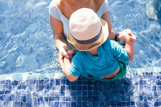 Mother and young son in outdoor swimming pool, elevated view, mid section