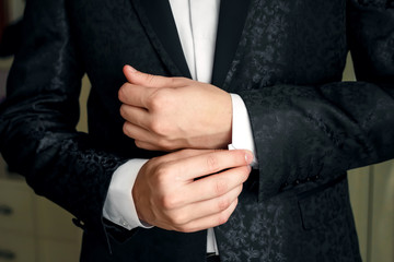 Obraz premium A man in a blue suit straightens his sleeves