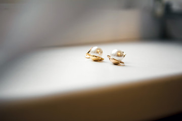 Beautiful earrings with pearls on a beige background