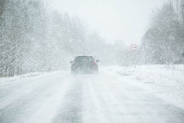 The car is driving on a winter road in a blizzard - obrazy, fototapety, plakaty