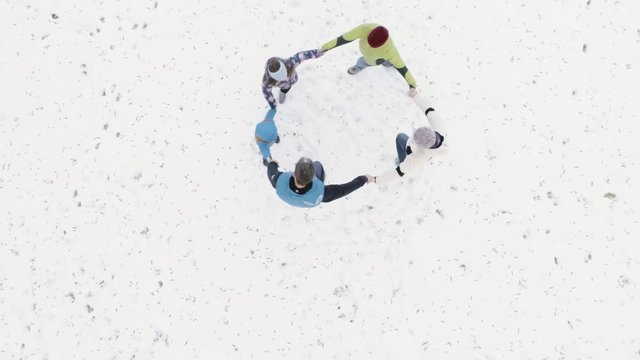 People playing ring around rosie in winter woods snow. Overhead aerial drone flight over playful family in mountain forest nature outdoors.straight-down perspective.Togetherness. 4k top view video