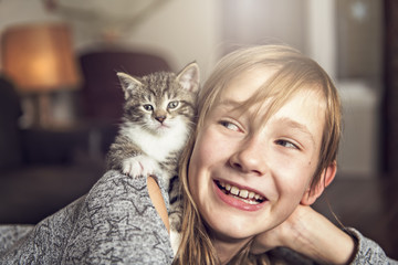 Preteen girl of 10 years old with her cat pet on the sofa