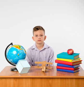 Cute schoolboy sit at a school desk isolated on white background. Ideal for banners, registration forms, presentation, school concept.