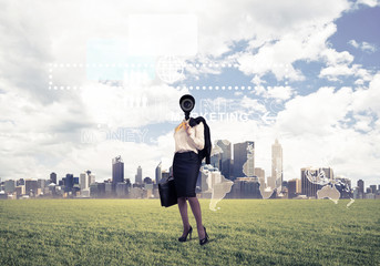 Camera headed woman standing on green grass against modern citys