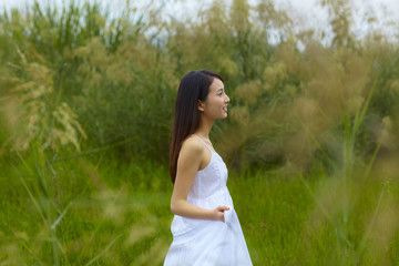 Fototapeta na wymiar pretty young asian woman outdoor in the meadow with white dress