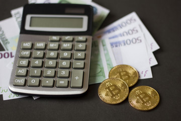 Golden bitcoins and banknotes Euro on a calculator on a black background. the new virtual money