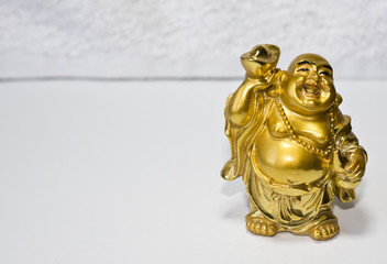 A statuette of a golden buddha. God Hotei is a laughing buddha.