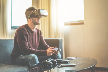 Young gamer playing video games virtual reality glasses in his apartment
