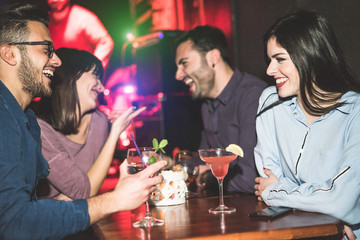 Happy friends having fun at club jazz bar - Young trendy people drinking tropical cocktails and laughing together - Party and nightlife concept - Focus on right woman face