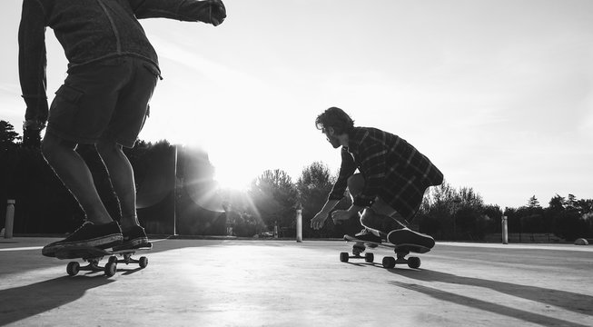 Two skaters friends training outdoor in city park at sunset - Young people skateboarding with longboard in urban contest - Extreme sport concept - Focus on right man legs feet - Vintage vsco filter