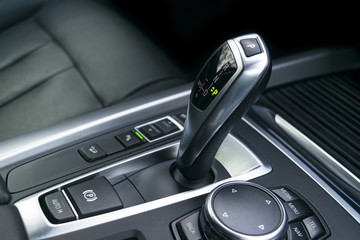 Fototapeta na wymiar Automatic gear stick (transmission) of a modern car, multimedia and navigation control buttons. Car interior details. Transmission shift.