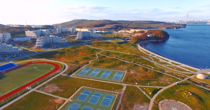 Campus of Far Eastern Federal University. Park, sports ground and buildings of university. Bay, bridge of Vladivostok on background. Aerial view.
