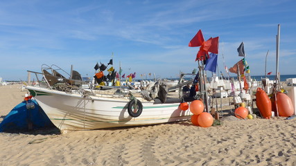Fischerboot mit vielen Bojen auf dem langen, breiten, feinsandigen Strand von Montegordo, Algarve,...