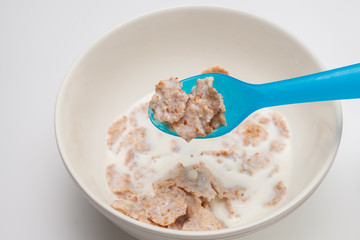 blue spoon and Breakfast cereals with milk in white bowl