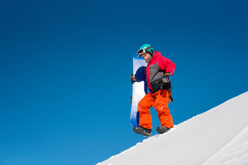 Fototapeta na wymiar Low angle full length shot of a fully equipped snowboarder walking down the slope carrying his snowboard copyspace nature outdoors winter recreation seasonal sport active lifestyle concept