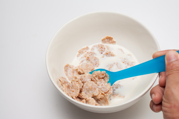 hand hold blue spoon .Breakfast cereals with milk in white bowl