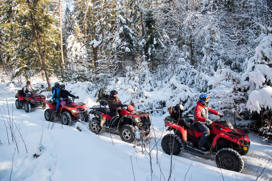 Group of people driving off-road four-wheelers ATV bikes in beautiful winter forest