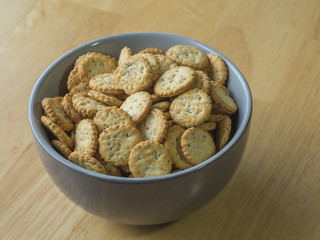 close up poppy seed sesame crunchy crackers in gray bowl on wooden table