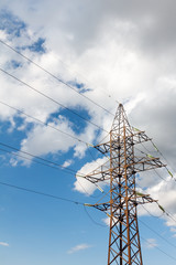 a high voltage power pylons against blue sky against the background of a cloud