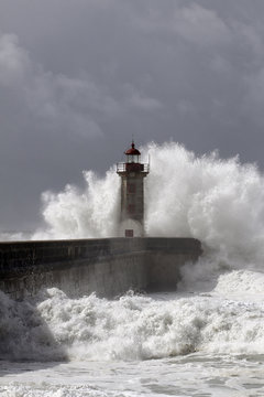 Stormy wave against pier and lighthouse