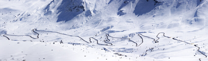 Panoramic view from Piz Boe towards Passo Pordoi, Sella Ronda slopes with skiers and ski lifts, local road cutting the picture in half