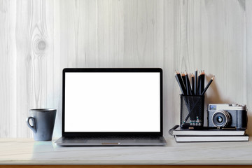 Mock up blank white laptop screen and camera with designer supplies on desktop.
