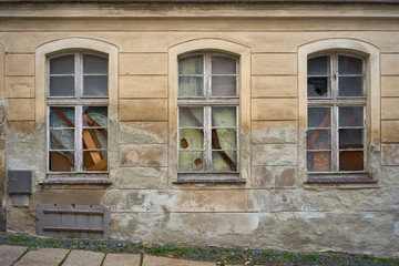 Broken and boarded-up windows in an old abandoned house