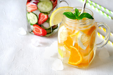 Summer refreshing iced drinks with orange, lemon, cucumber and strawberry on white background