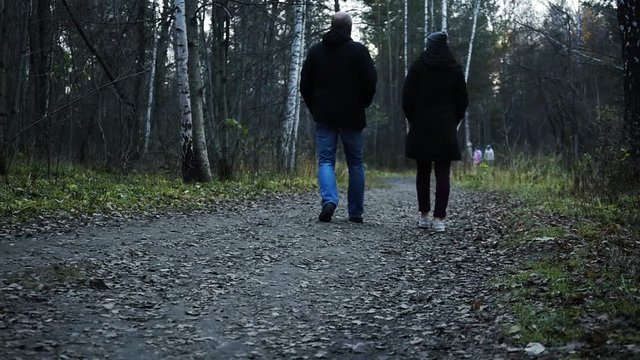 A man and a woman are walking in the autumn park in the evening. HD, 1920x1080, slow motion