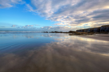 Cielo azul  reflejado en el agua de la playa