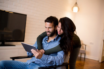 Young couple sitting in the living room and using tablet