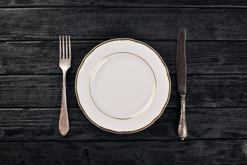 Plate and old cutlery. On a wooden background. Top view. Free space for text.