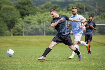 Football players playing soccer in the ground