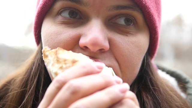 A girl with hungry eyes eats shawarma with pleasure, vegetables stick out of her mouth. HD, 1920x1080, slow motion