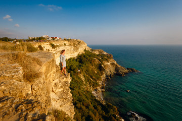 Beautiful young girl enjoying her vacation by the sea,  relaxed, concept of freedom.Woman on the beautiful natural rock arch. Amazing blue green sea and sunny day.