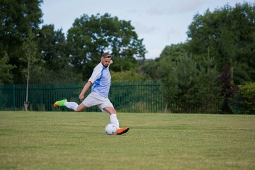 Football player kicking the soccer on the football ground