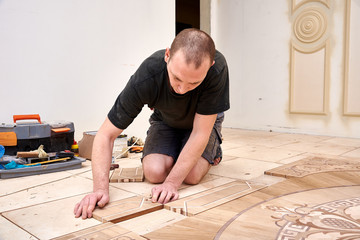 The carpenter installs one of the decorative elements of the parquet.