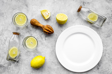 Obraz na płótnie Canvas Fresh homemade lemonade. Lemons, juicer, glass for beverage on grey stone background top view mockup