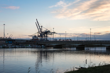 Fototapeta na wymiar Container Terminal, Shipyard and Cranes at Sunset and Their Refl