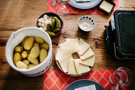 Swiss traditional dish called raclette including steamy potatoes, melted cheese and pickles eaten at christmas and wintertime