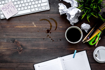 Clutter in office. Desk covered with crumpled paper and coffee stains. Dark wooden background top...