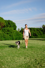 Pregnant woman enjoying summer walk at the park with her dog.