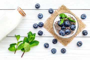 Eat chia seeds for breakfast with yogurt, blueberry and mint. White wooden background top view