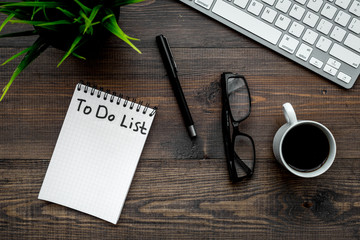 To do list for businessman in notebook on office table. Dark wooden background top view