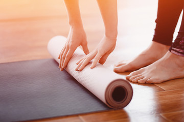 Yoga. Close-up woman folding roll fitness or yoga mat after working out home in living room....