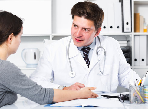 Cheerful professional doctor in uniform talking with patient