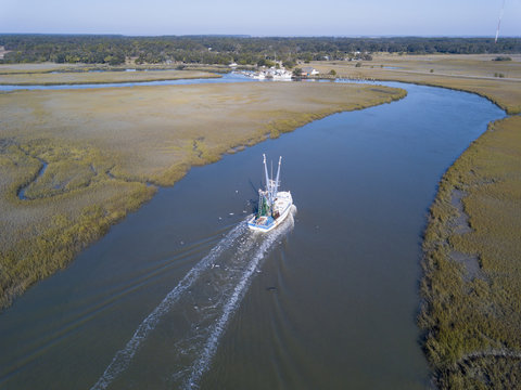 Aerial view of shrimp boat coming into port.