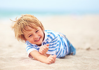 Fototapeta na wymiar cute happy laughing boy, kid having fun on sandy beach, summer vacation